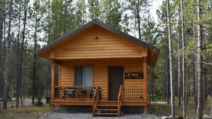 A wooden cabin with a porch, a small front door, and a sign that reads "Tiny Timber." - Tiny Timber-28 miles to Yellowstone (Island Park)