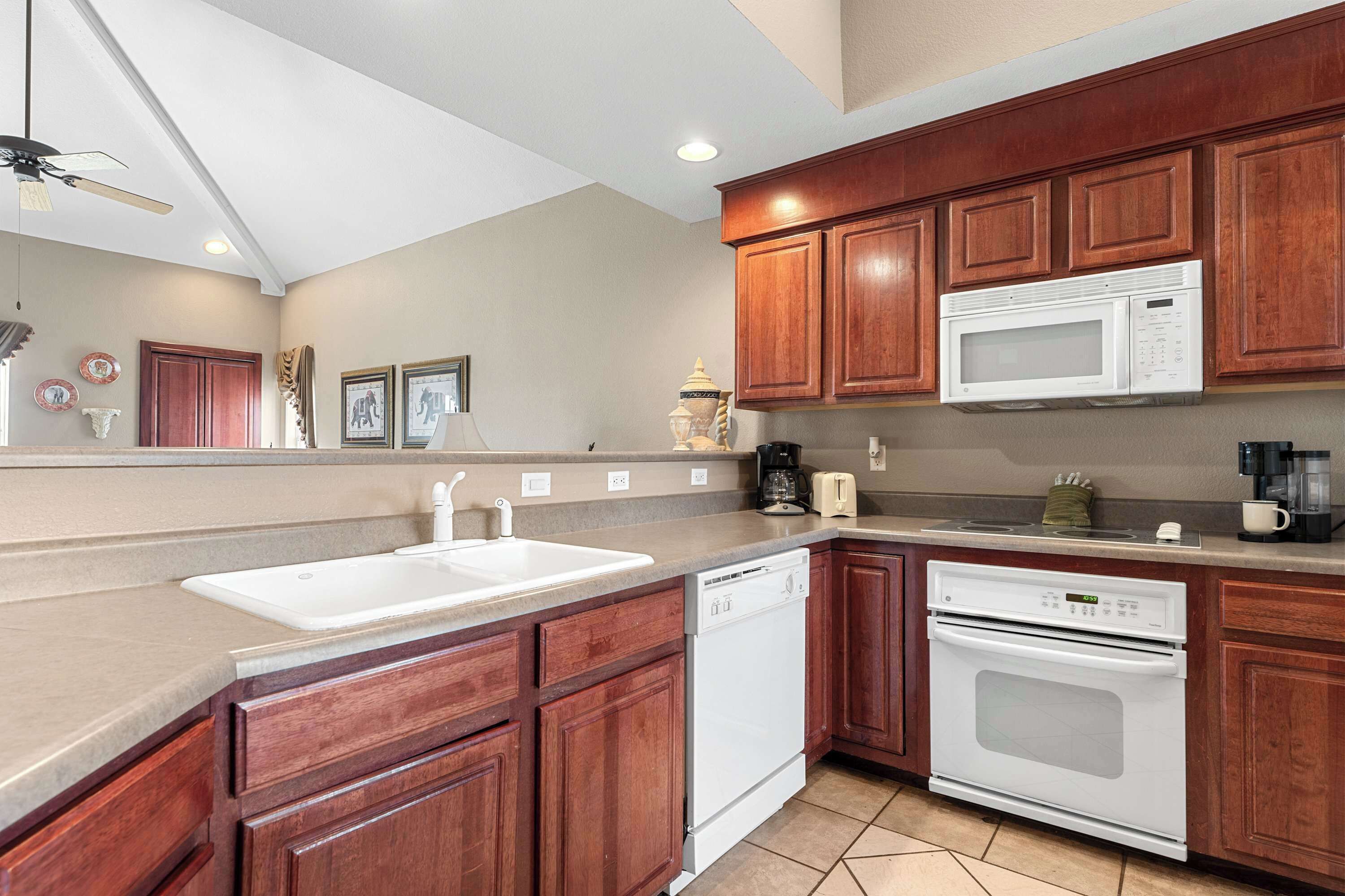 A kitchen with wooden cabinets, a white sink, a dishwasher, a microwave, and an oven.