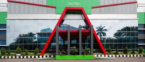 Un edificio moderno con una fachada destacada de color rojo y verde, con el letrero