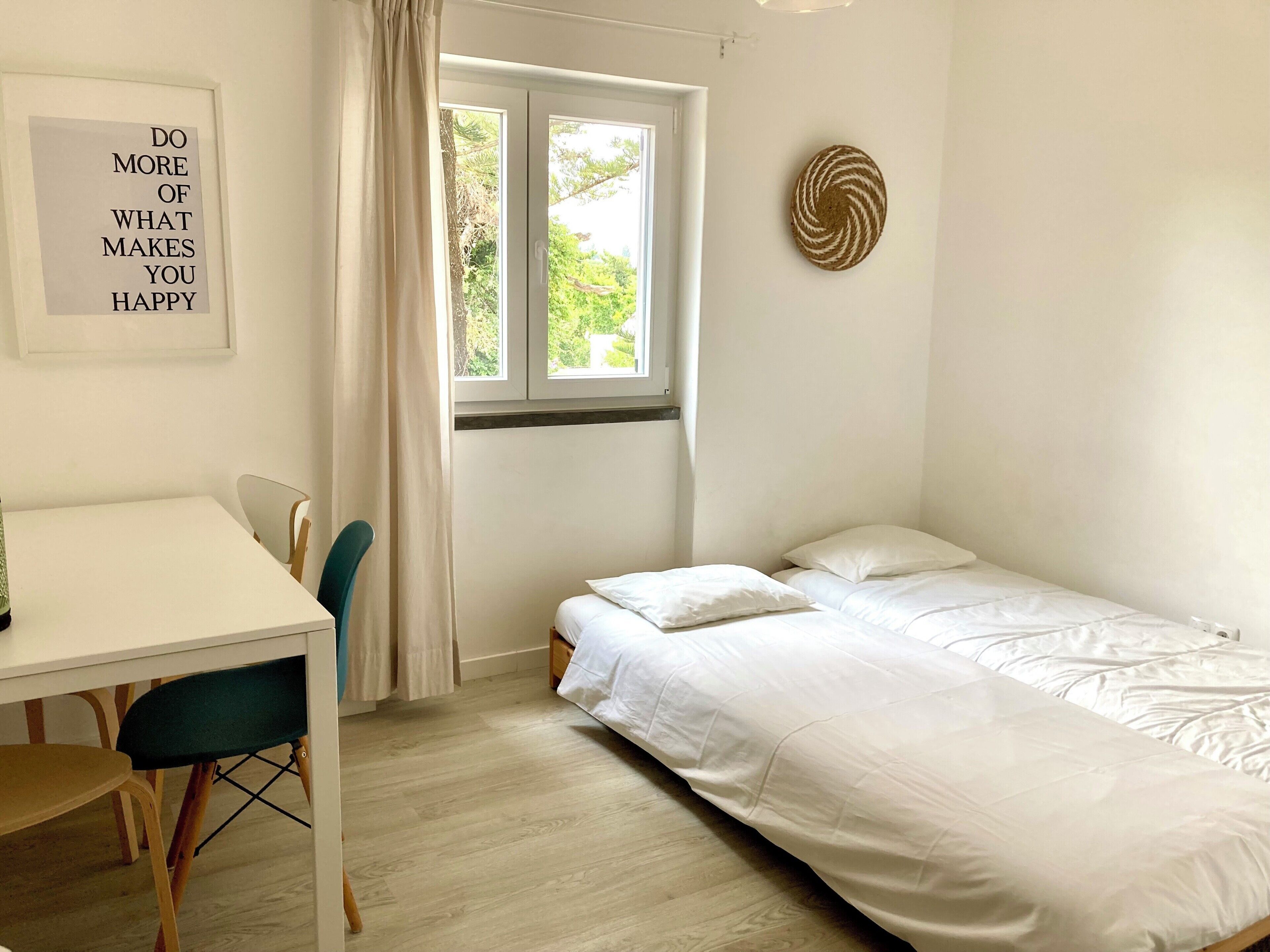 Une pièce comprenant un lit, un bureau, une chaise, une fenêtre avec des rideaux et une affiche motivante accrochée au mur.