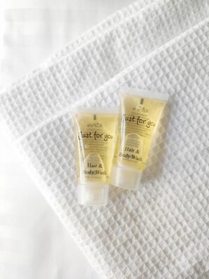 Two tubes of hair and body wash on a textured white surface.