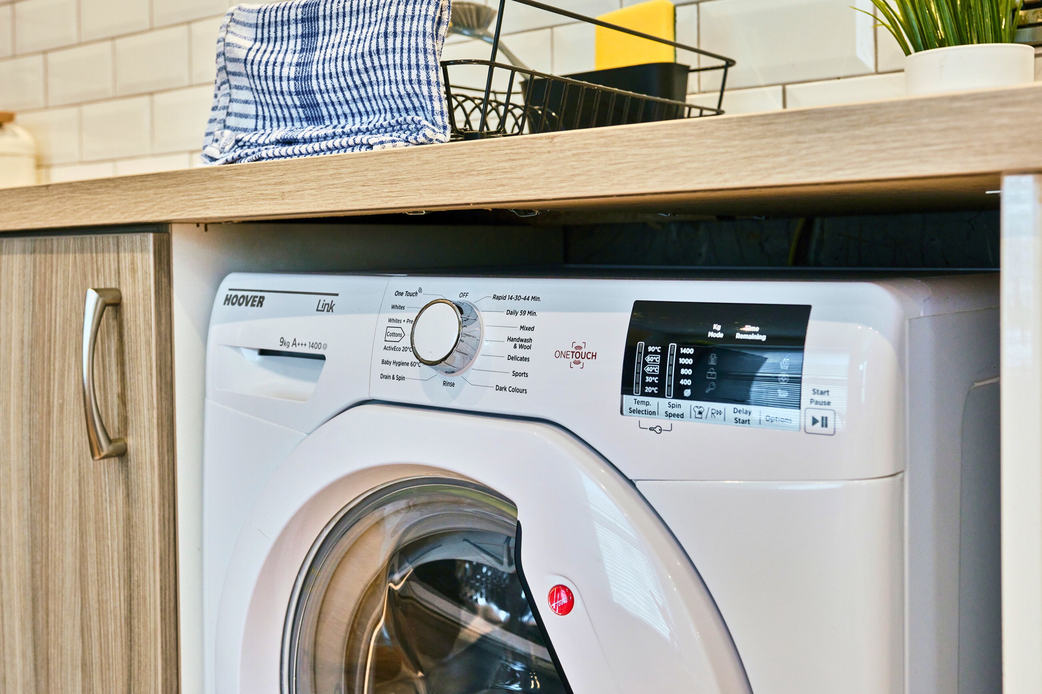A front view of a modern washing machine with a control panel, a digital display, and a stainless steel door.