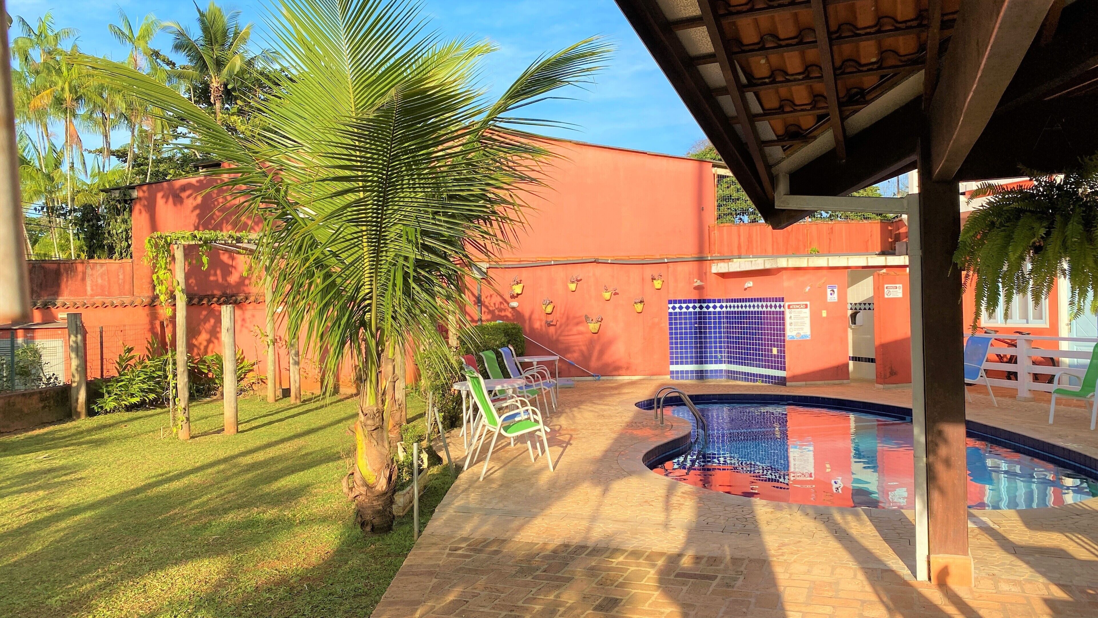 A pool area with a tiled deck, lounge chairs, and a covered seating area.