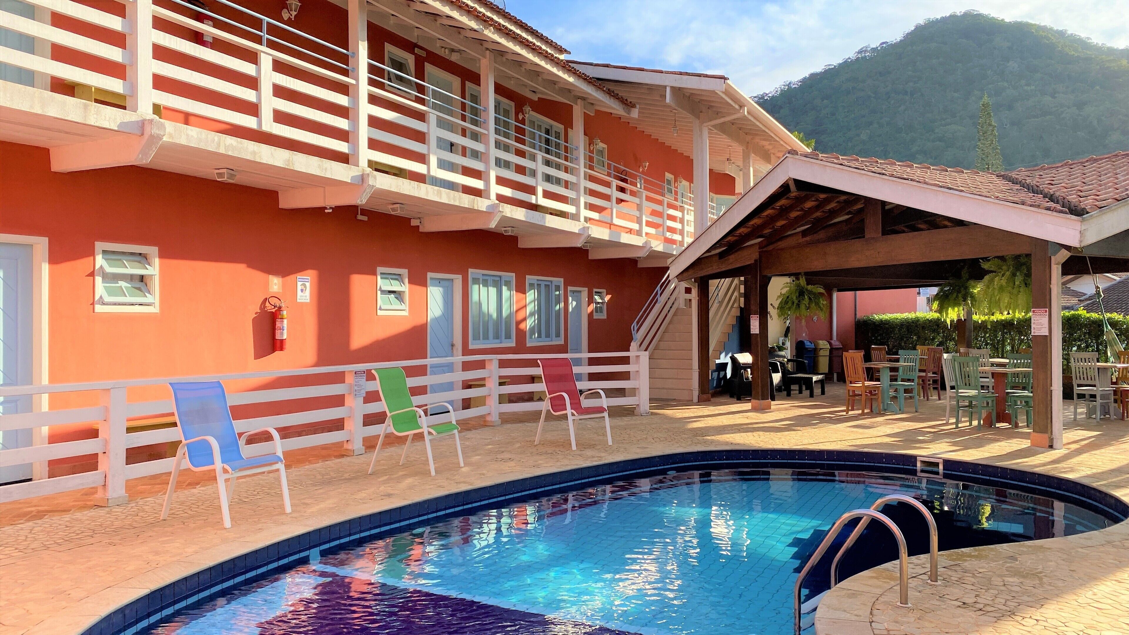 Um hotel com piscina, área de estar ao ar livre e montanhas ao fundo.
