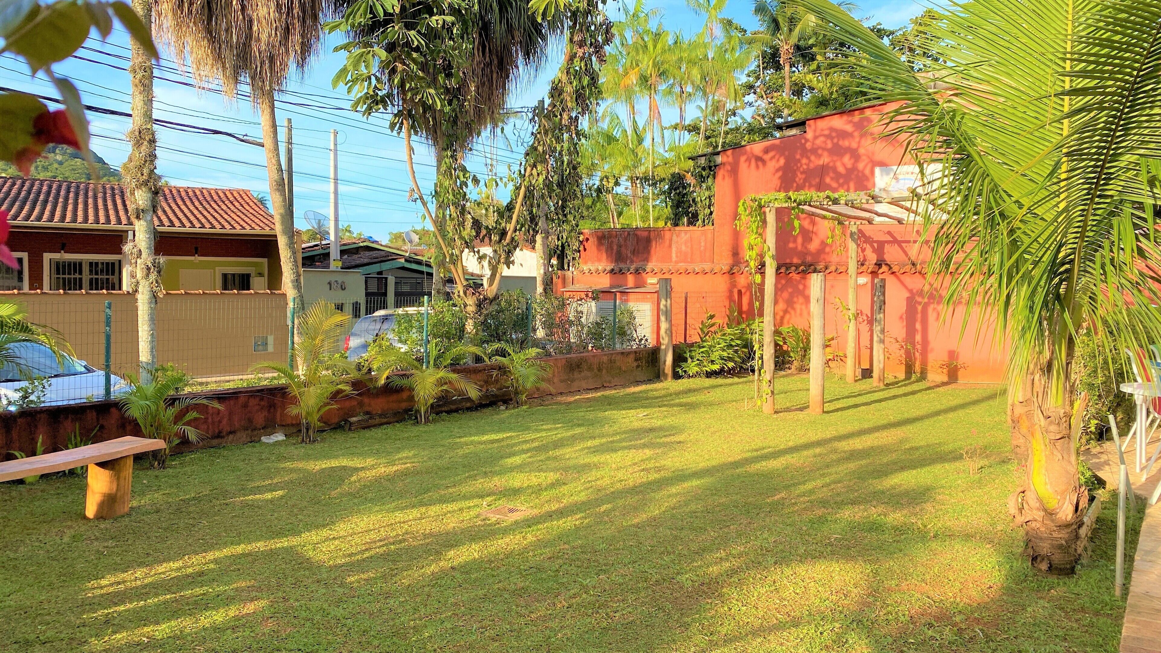 Un jardin bien entretenu, avec une pelouse, un banc en bois et une variété de plantes et d’arbres.