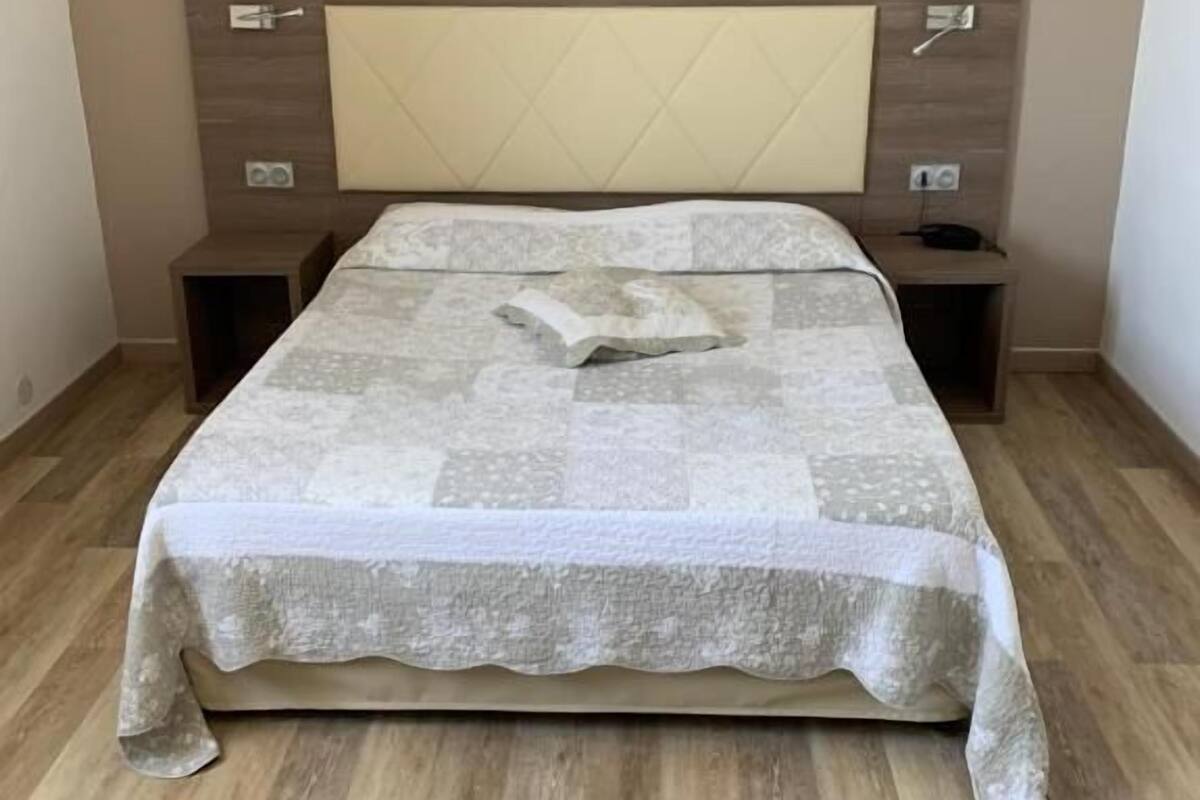 Ein Schlafzimmer mit einem Bett, Nachttischen, einer Wandleuchte und Holzboden.