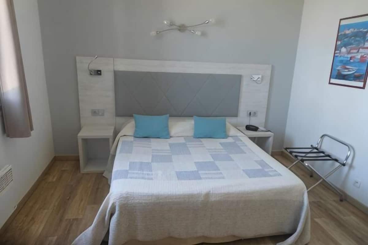 Ein Schlafzimmer mit einem Bett, Nachttischen, einem Kopfteil und einer Wandleuchte.