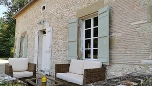 Un bâtiment en pierre avec deux canapés en osier et une petite table.