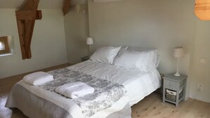 Une chambre à coucher avec un lit, une table de chevet, une lampe et un plafond en bois.
