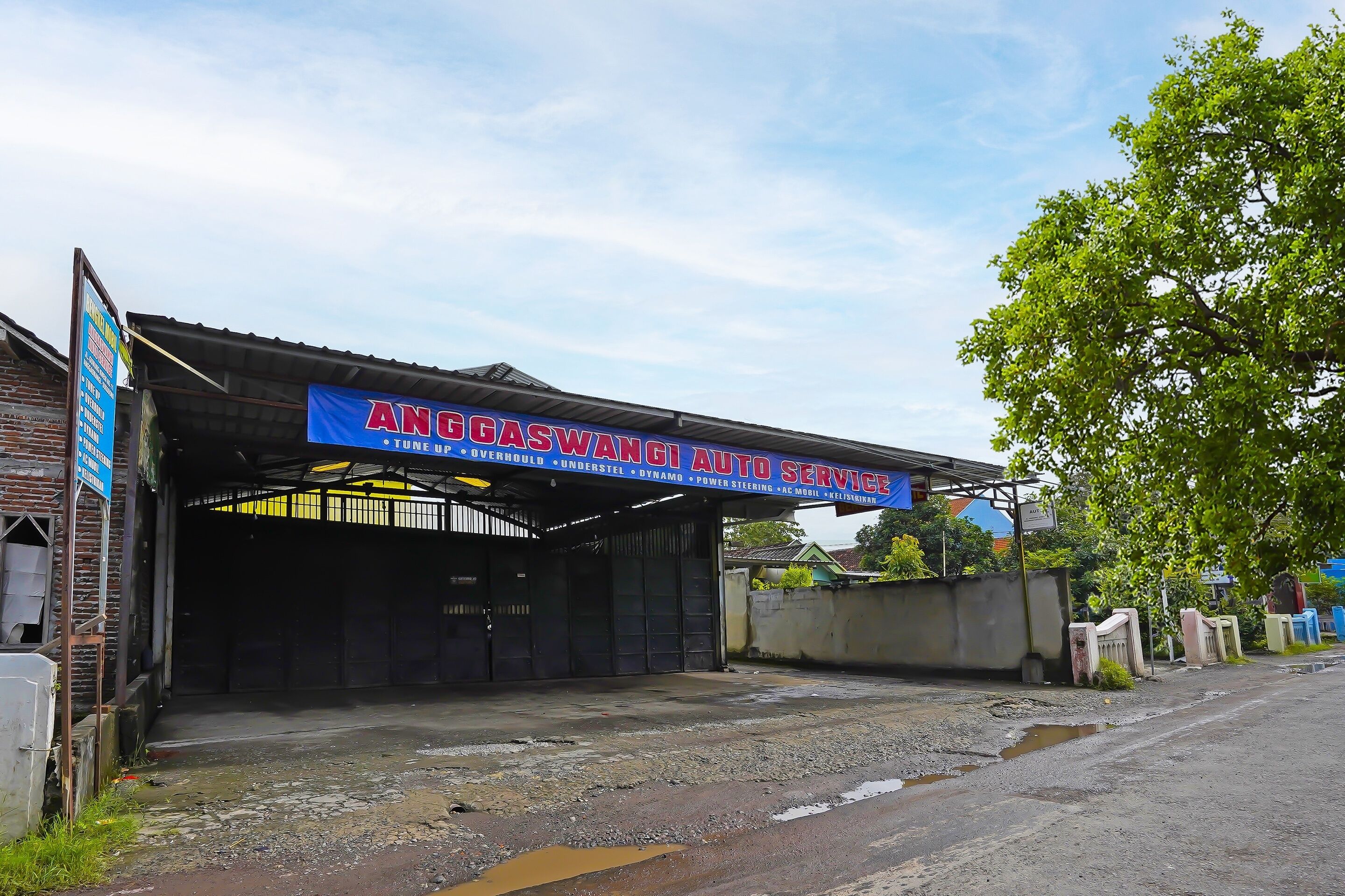 Un bâtiment avec une enseigne indiquant « ANG GASWAN AUTO SERVICE » et une entrée abritée.