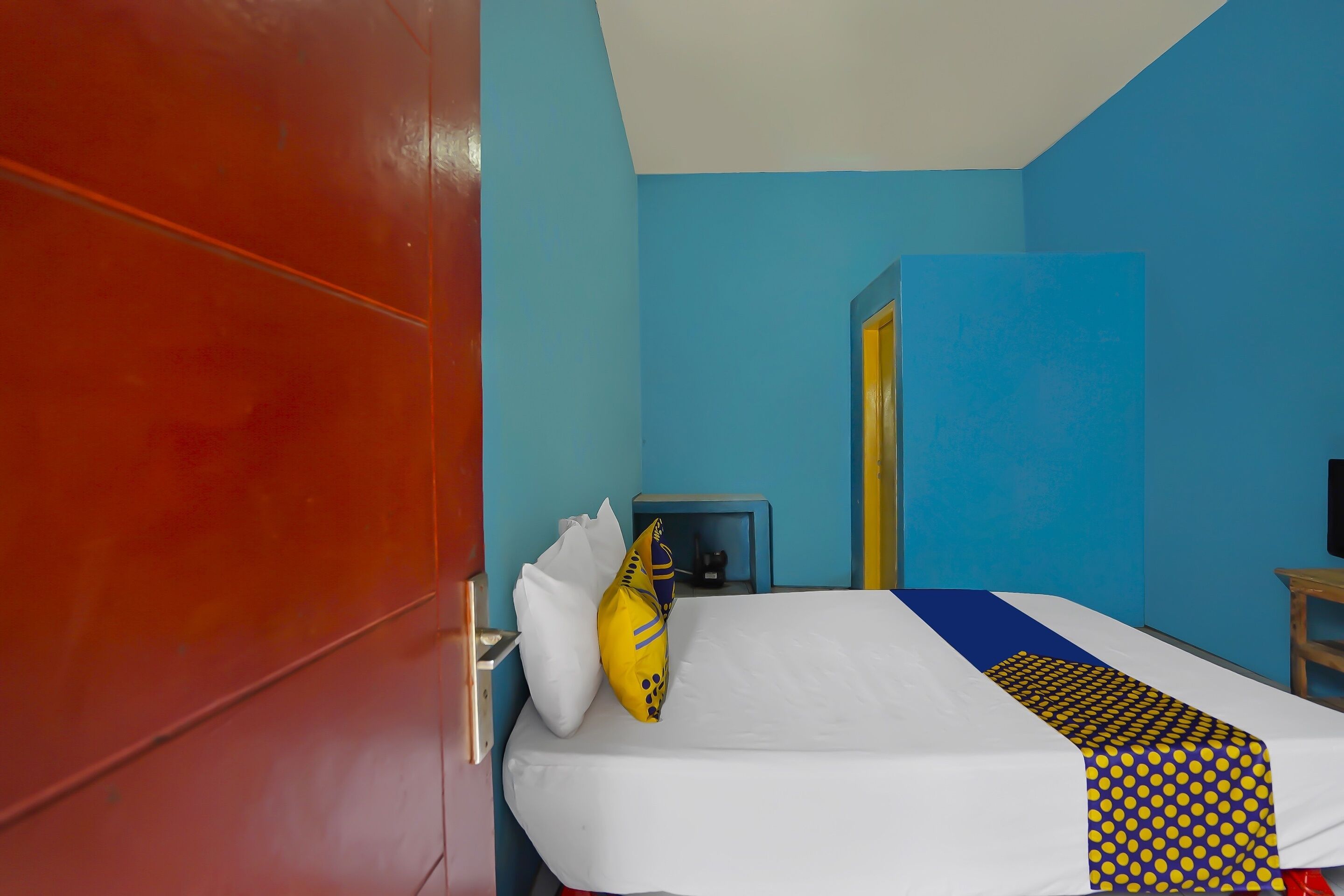 Una habitación de hotel con cama, mesita de noche, televisión y puerta.