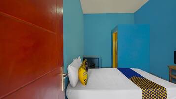 Una habitación de hotel con cama, mesita de noche, televisión y puerta.