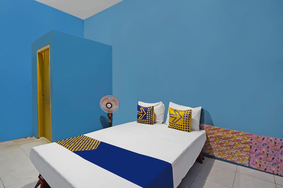 Un dormitorio con cama, ventilador y pared colorida.