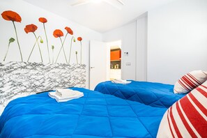 Une chambre d’hôtel avec deux lits, une tête de lit en marbre et une décoration murale représentant des coquelicots.
