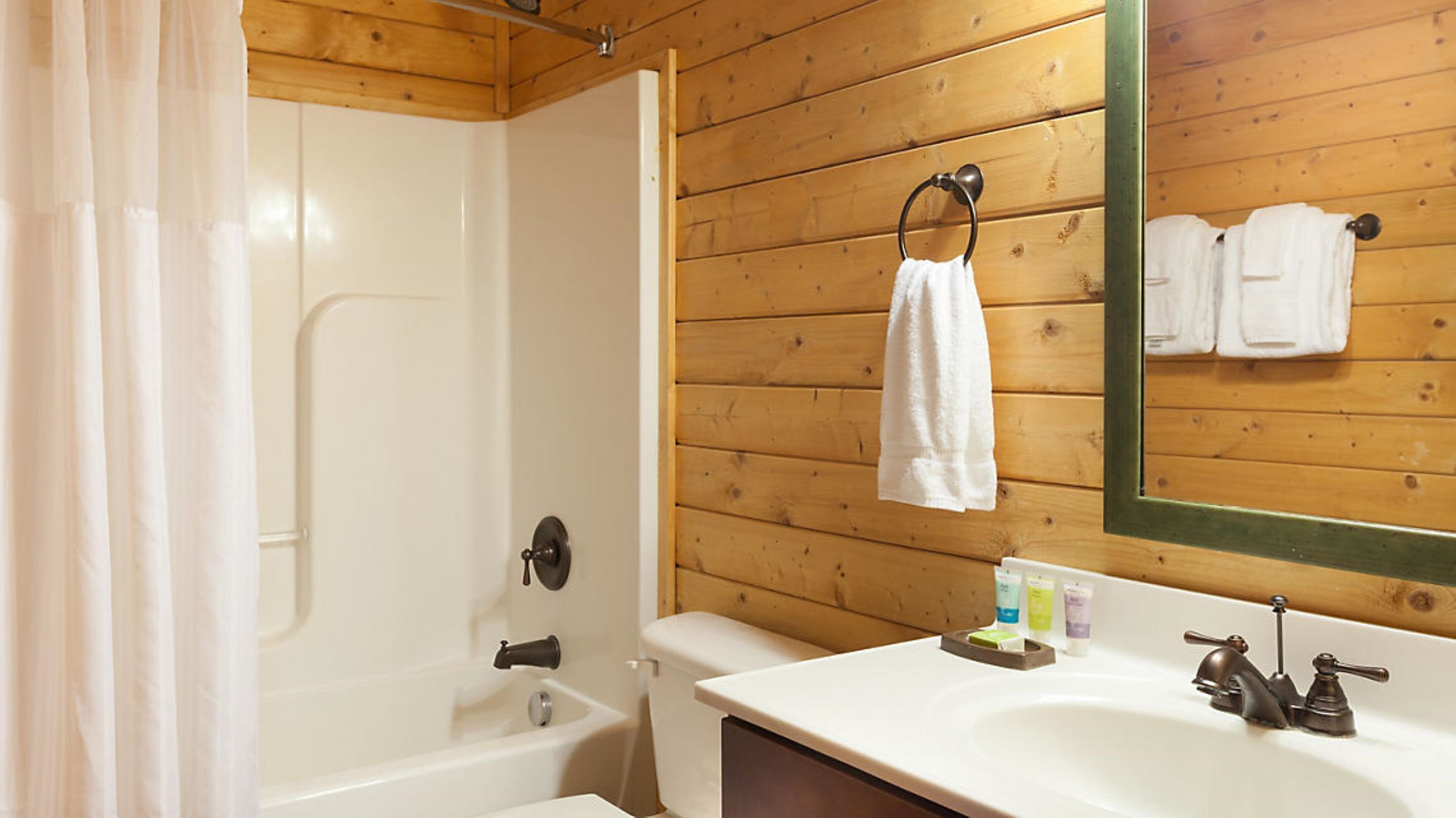 Une salle de bain équipée d’une douche, de toilettes, d’un lavabo et d’un miroir, avec une serviette accrochée au mur.