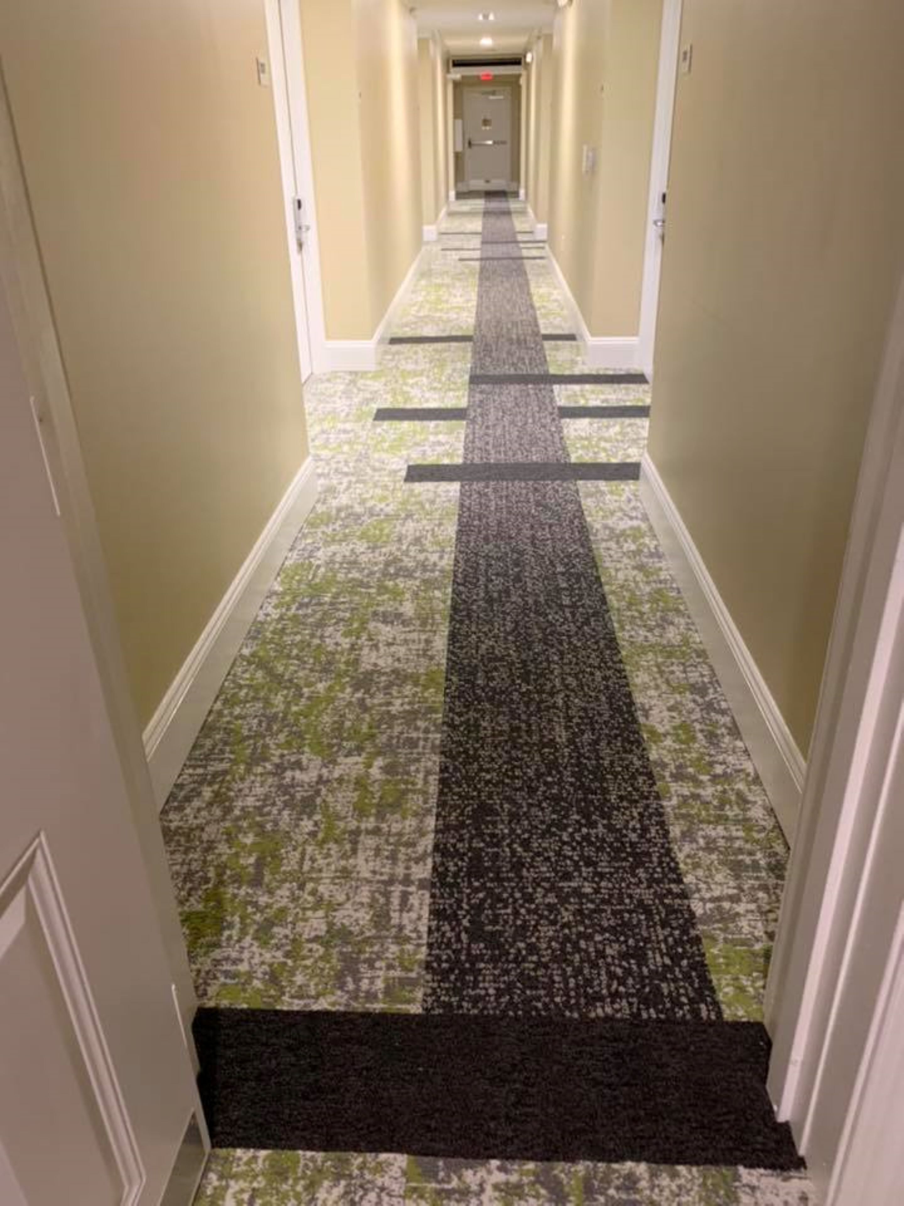 A hotel hallway with carpeted floors and doors on either side.