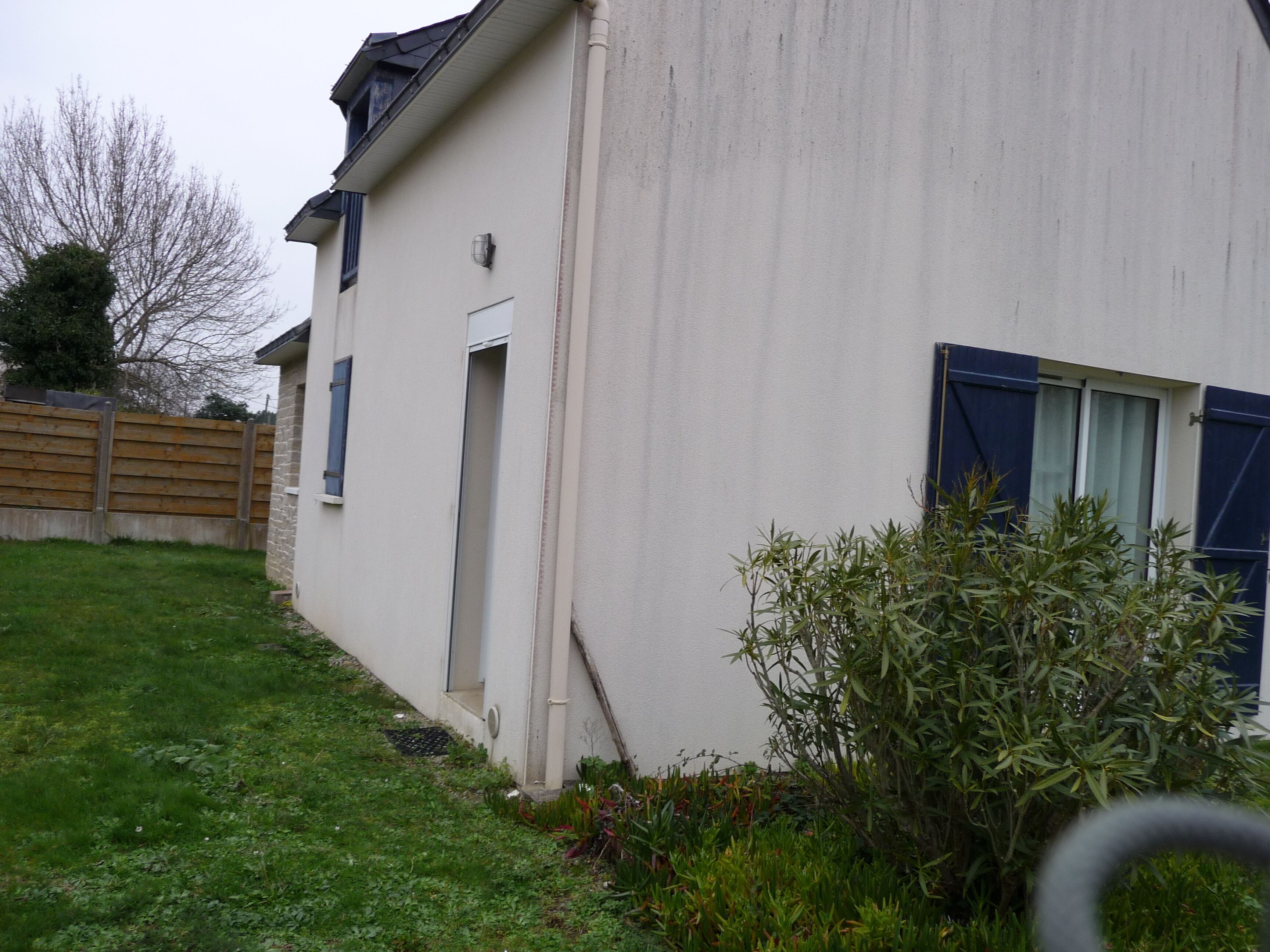 A house with a white exterior, a wooden fence, and a garden.