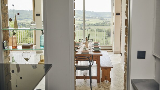 Un comedor con una mesa preparada para cuatro personas, con vistas a un paisaje pintoresco.