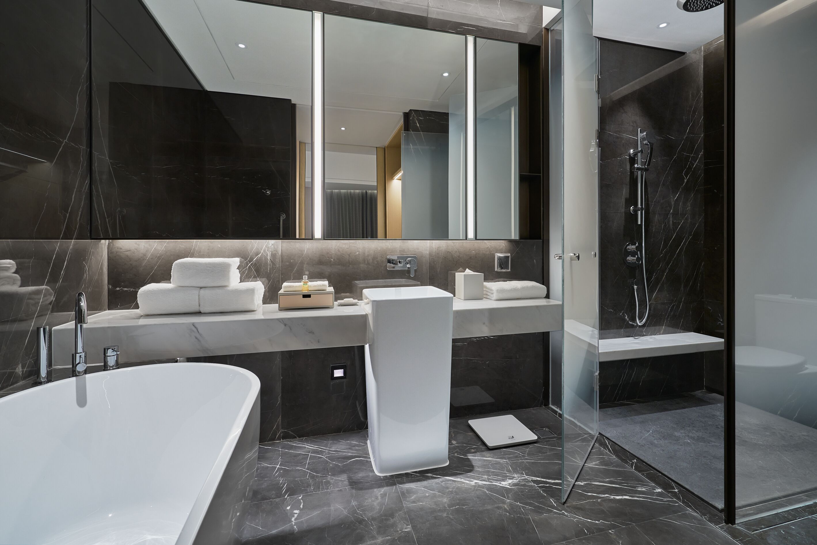 Een moderne badkamer met een groot bad, een douche met glazen wanden en een vloer van marmer.