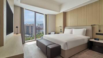 Un moderno cuarto de hotel con una cama grande, un escritorio, una silla, un televisor y vistas a la ciudad.