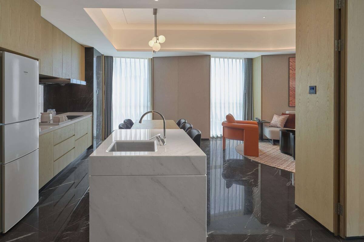 A modern kitchen with a central island, a built-in oven, and a refrigerator.