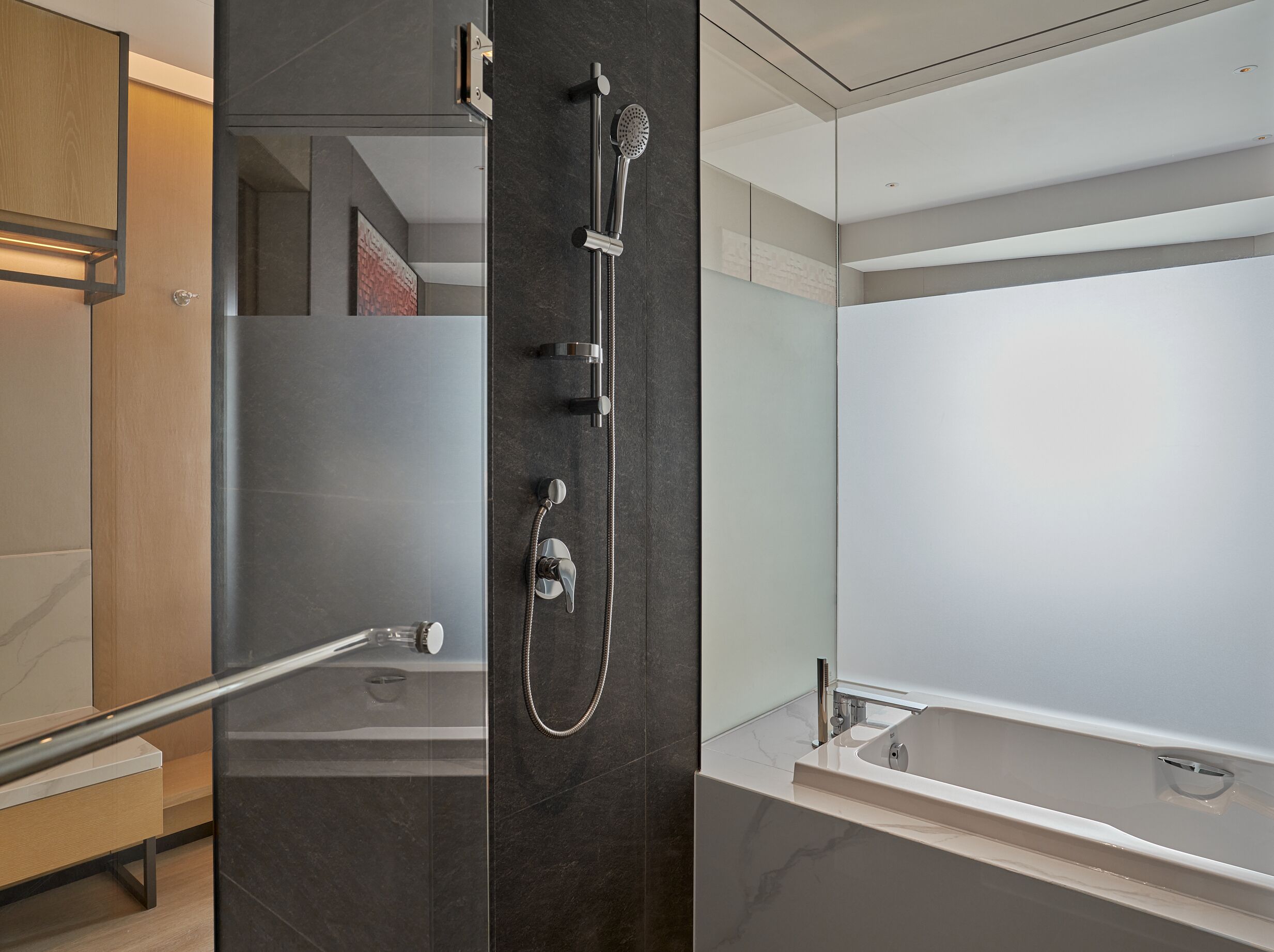 Un baño moderno con cabina de ducha de vidrio, bañera independiente y tocador de madera.