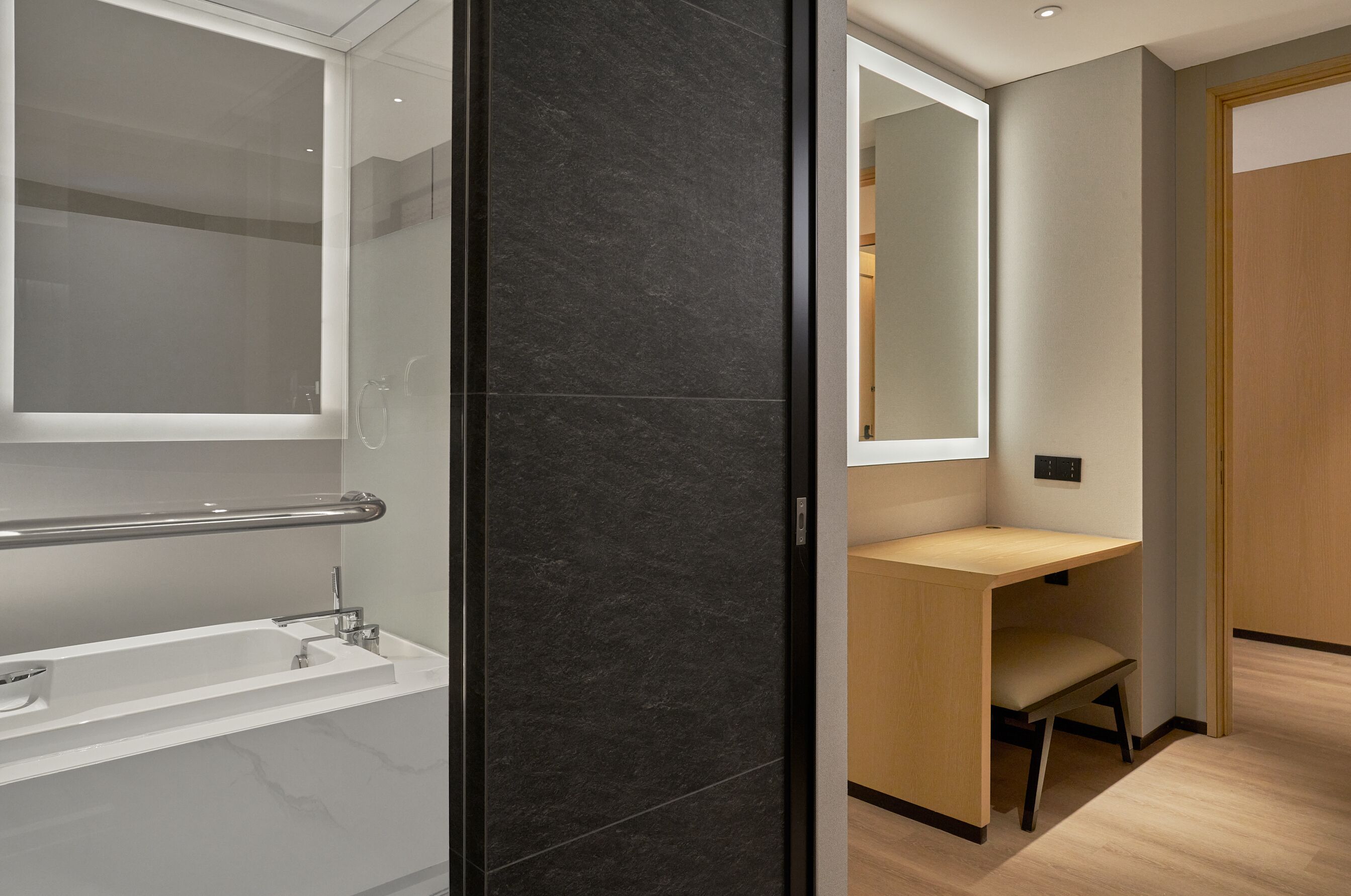 Ein modernes Badezimmer mit einer Badewanne, einem Waschtisch mit Spiegel und einer hölzernen Sitzbank.