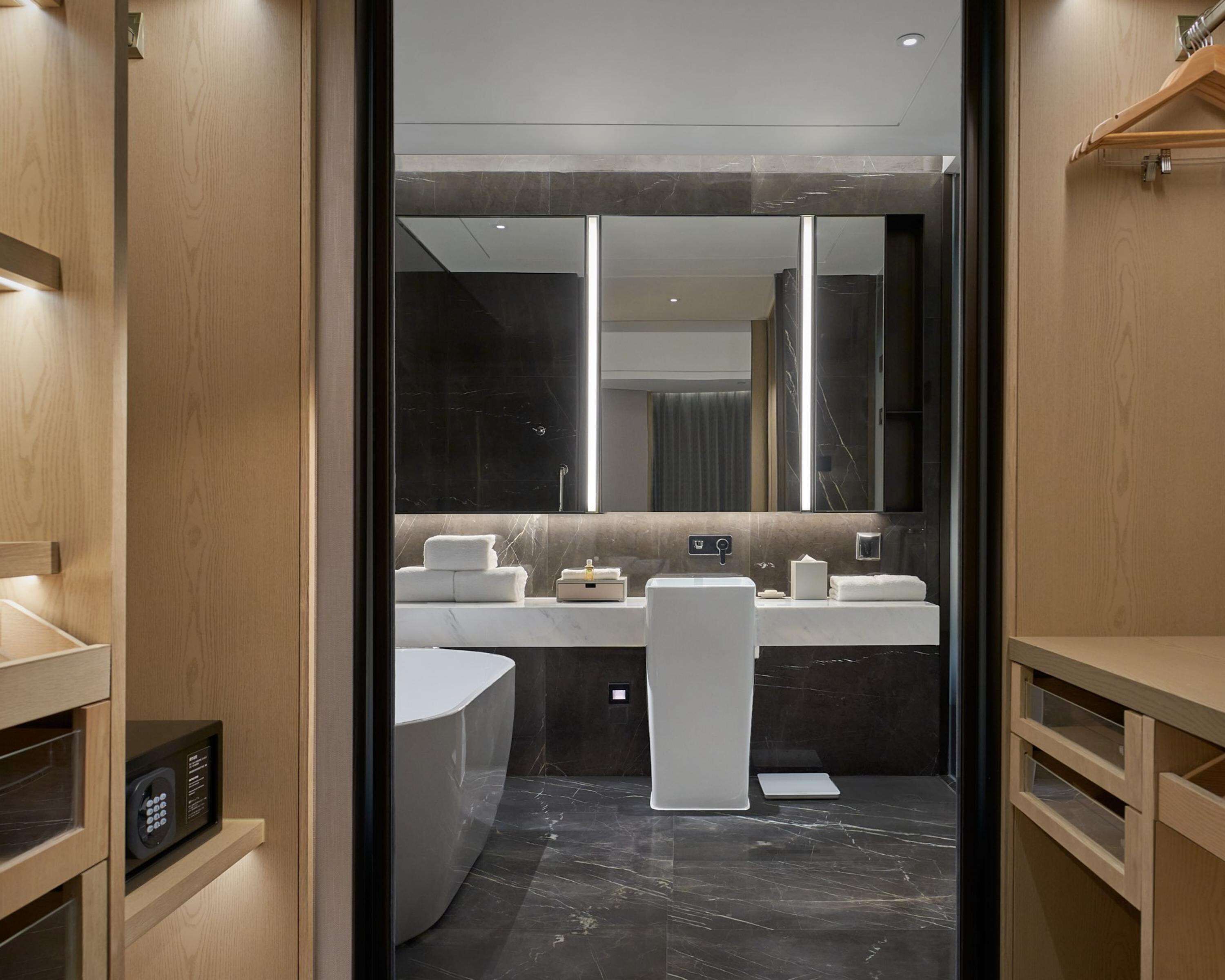 Un baño moderno con un espejo grande, dos lavamanos y una bañera.