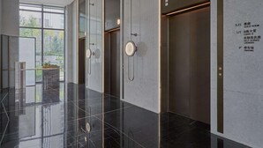 A modern elevator area with clear signage for guest rooms, a lobby, self-service laundry, and parking.