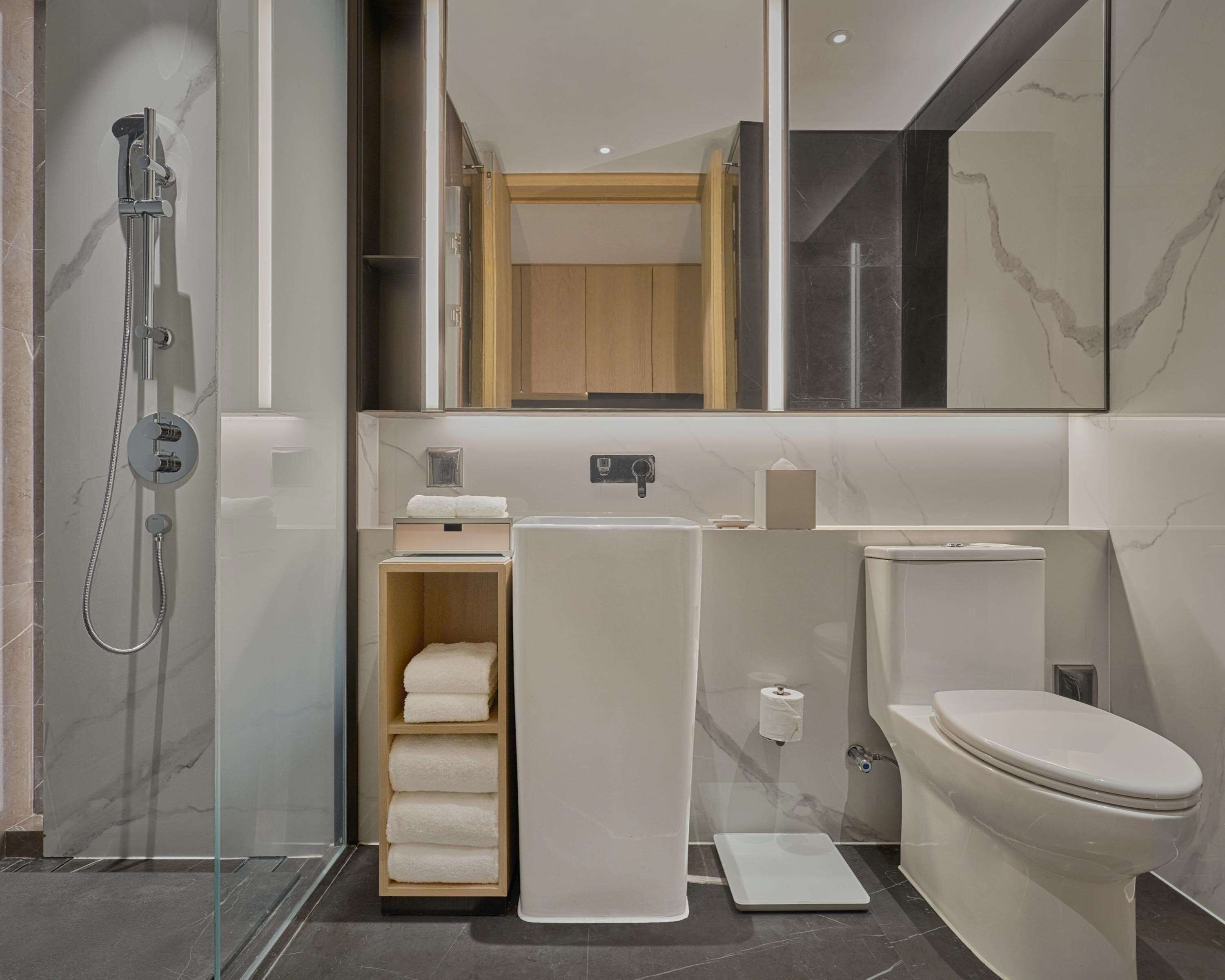 A modern bathroom with a glass-enclosed shower, a toilet, and a towel rack.