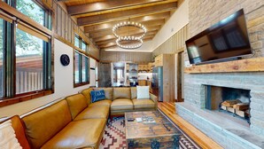 A cozy living room with a leather sofa, a fireplace, and a television mounted on the wall. - Private Hot tub, 1mi to Shangri La, next to Battlefield Par 3, & Walk to Lake (Afton)