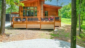 A wooden cabin with a deck, large windows, and a stone chimney. - Private Hot tub, 1mi to Shangri La, next to Battlefield Par 3, & Walk to Lake (Afton)
