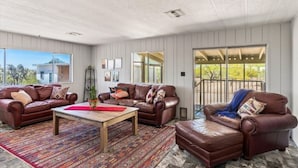 A spacious living room with two leather sofas, a coffee table, and a patterned rug. - Cosy Desert Hideaway (Tucson)