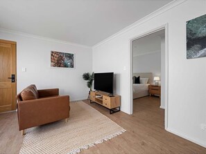 A modern living room with a sofa, TV, and a small side table.
