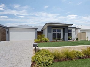 A modern two-story house with a garage, a well-maintained lawn, and a mailbox.