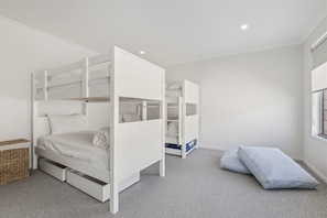 A room with bunk beds, a small storage unit, and a window.