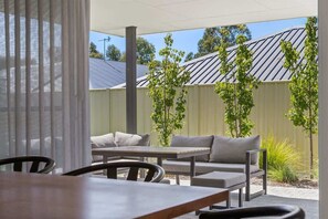 An outdoor patio area with a table and chairs, a sofa, and a covered seating area.