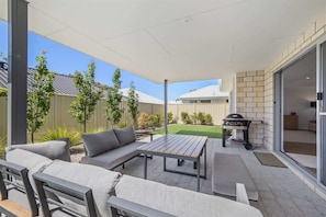 An outdoor patio area with a sofa, a table, and a barbecue grill.