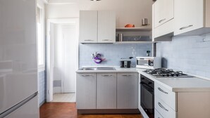Una cucina moderna con mobili bianchi, piano cottura a gas, forno a microonde e lavandino.