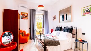 A bedroom with a bed, a chair, a table, and a mirror. - Art House Arenella con Terrazze by Wonderful Italy (Palermo)