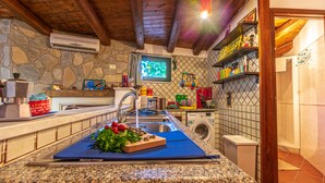 A kitchen with granite countertops, a stone wall, a washing machine, and a window with a view. - Art House Arenella con Terrazze by Wonderful Italy (Palermo)