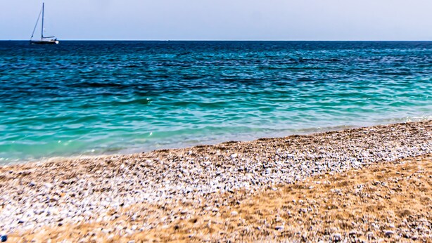 A beach with pebbles and a sailboat in the water. - Art House Arenella con Terrazze by Wonderful Italy (Palermo)