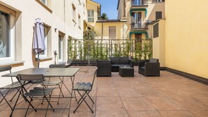 A courtyard with outdoor seating, including a table and chairs, surrounded by buildings with balconies and windows. - Design Suite in Bologna by Wonderful Italy (Bologna)