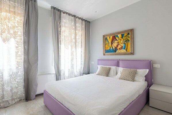 A bedroom with a bed, a nightstand, a painting, and a window with curtains. - Design Suite in Bologna by Wonderful Italy (Bologna)