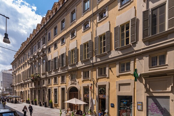 A historic building with multiple stories, large windows with shutters, and outdoor seating areas with umbrellas. - Duplex Apartment Pura Vida By Wonderful Italy (Turin)