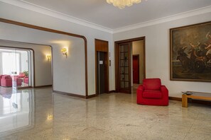 A spacious lobby with a polished floor, a red armchair, a bench, and a large painting on the wall. - Eden Vista Mare con Piscina by Wonderful Italy  (Genoa)