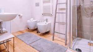 Ein modernes Badezimmer mit Waschbecken, Bidet und Duschkabine aus Glas.