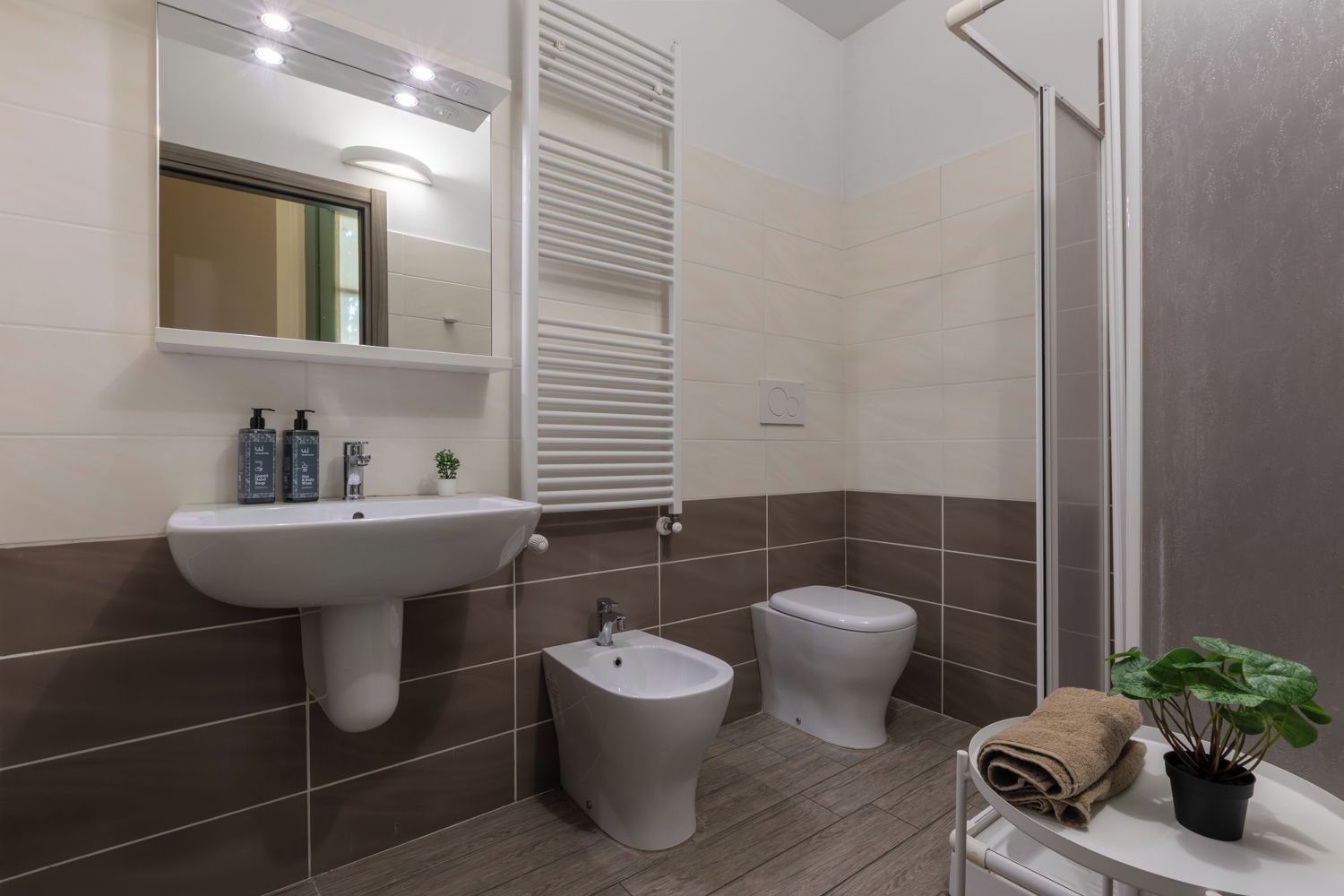 Un baño moderno con lavamanos, bidé, inodoro y zona de ducha.
