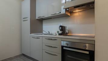 Una cucina compatta con forno integrato, macchina del caffè e lavello.