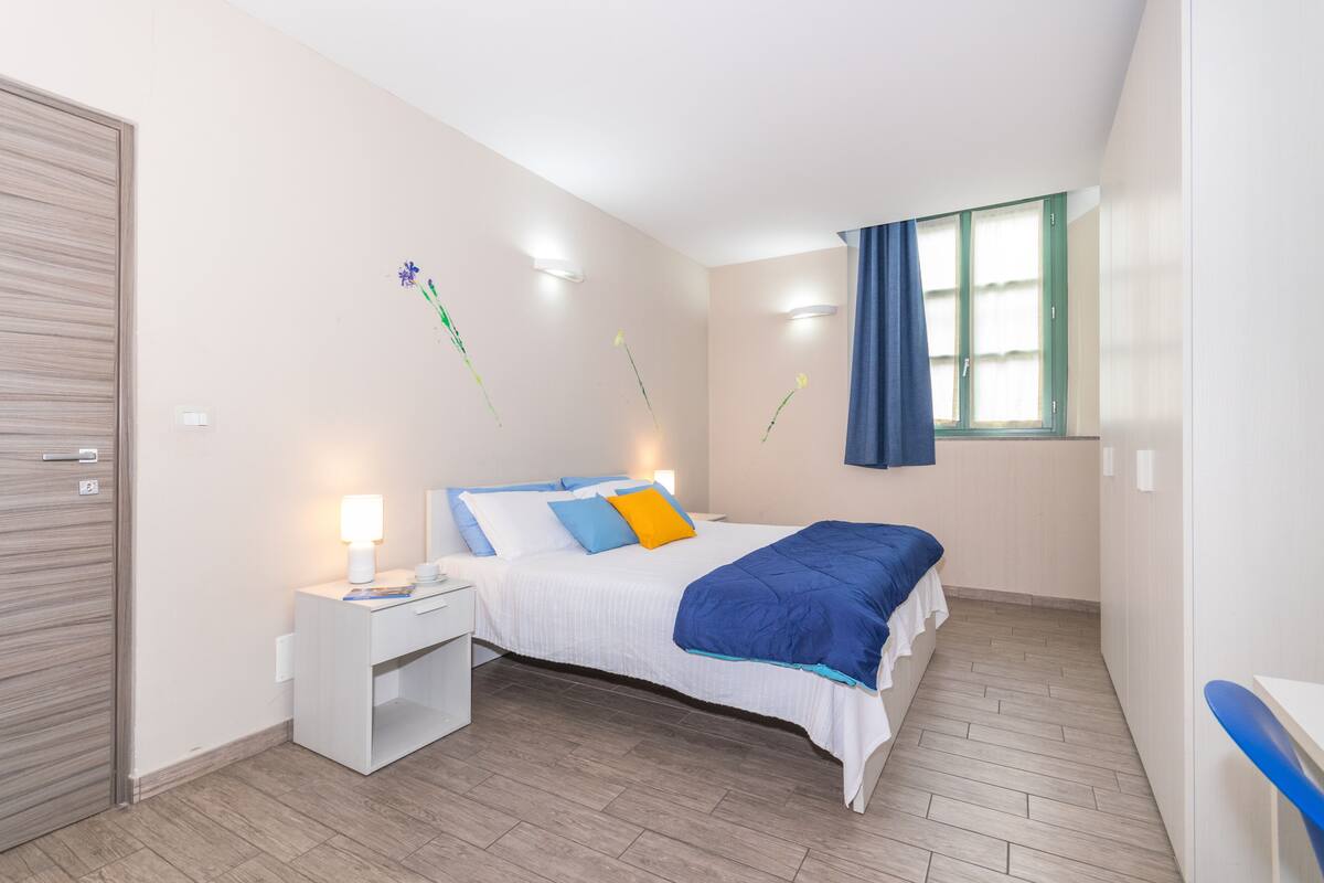 A bedroom with a bed, bedside table, and a window with curtains.